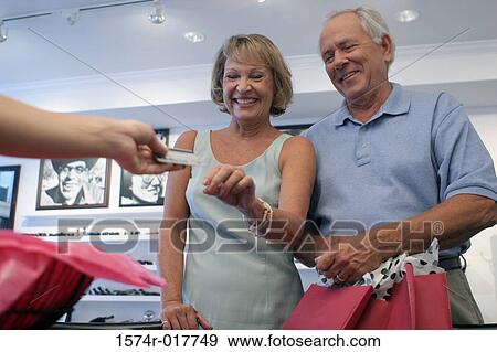 Low angle view of a senior couple handing a credit card to a person View Large Photo Image Stock Photo - Low angle view of a senior couple handing a credit card to a person. Fotosearch