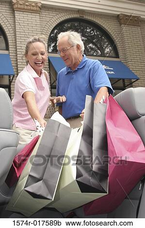 Stock Image - Senior couple putting shopping bags in their car. Fotosearch