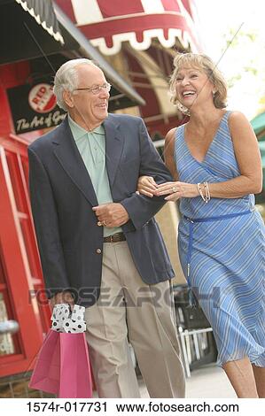 Stock Image - Senior couple walking with shopping bags. Fotosearch