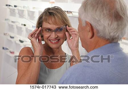 Senior woman trying on sunglasses in a store View Large Photo Image Stock Image - Senior woman trying on sunglasses in a store. Fotosearch