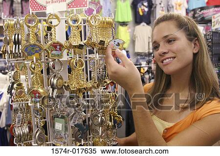 Side profile of a young woman looking at key rings in a store View Large Photo Image Stock Photography - Side profile of a young woman looking at key rings in a store. Fotosearch