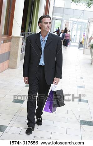 Stock Photograph - Young man carrying shopping bags. Fotosearch