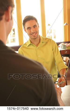 Stock Image - Young man handing a credit card to a sales clerk. Fotosearch