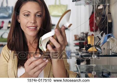Young woman holding a sandal in a shoe store View Large Photo Image Stock Image - Young woman holding a sandal in a shoe store. Fotosearch