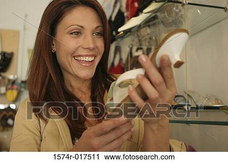Young woman holding a sandal in a shoe store View Large Photo Image Stock Image - Young woman holding a sandal in a shoe store. Fotosearch