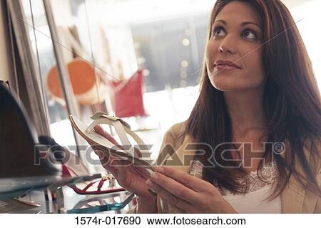 Stock Image - Young woman holding a sandal in a shoe store. Fotosearch