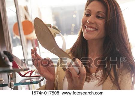 Stock Photo - Young woman holding a sandal in a shoe store. Fotosearch