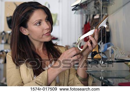 Stock Photo - Young woman holding a sandal in a shoe store. Fotosearch
