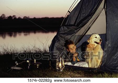 Stock Image - Boy camping in a tent with his dog. Fotosearch