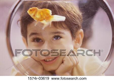 Stock Photo - Boy looking at a goldfish in a bowl. Fotosearch