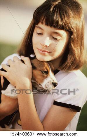 Stock Photo - Close-up of a girl holding her puppy. Fotosearch