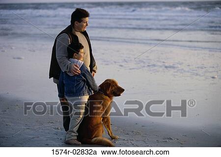 Stock Image - Father and his son with their dog on the beach. Fotosearch