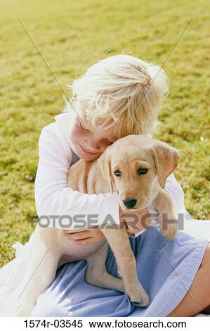 Girl sitting on a lawn holding a puppy View Large Photo Image Stock Photography - Girl sitting on a lawn holding a puppy. Fotosearch