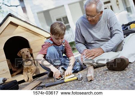 Stock Photo - Grandfather building a kennel with his grandson. Fotosearch