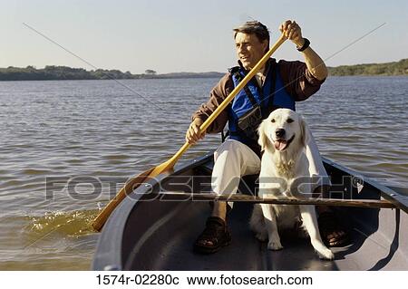 Stock Image - Mid adult man in a row boat with his dog. Fotosearch