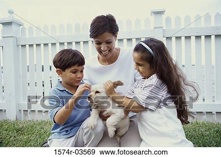 Mother with her son and daughter petting a puppy View Large Photo Image Stock Photo - Mother with her son and daughter petting a puppy. Fotosearch