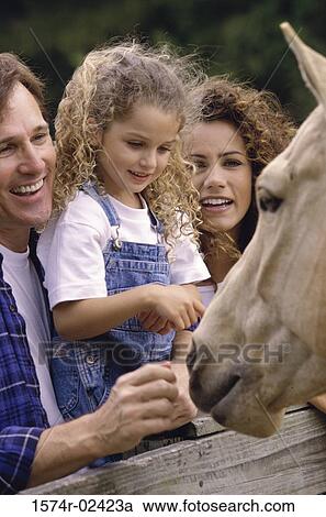 Parents with their daughter standing in front of a horse View Large Photo Image Stock Image - Parents with their daughter standing in front of a horse. Fotosearch