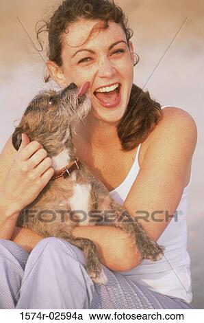 Stock Image - Portrait of a young woman holding her dog. Fotosearch