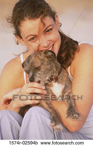 Stock Image - Portrait of a young woman holding her dog. Fotosearch