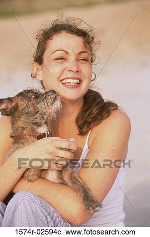Stock Image - Portrait of a young woman holding her dog. Fotosearch