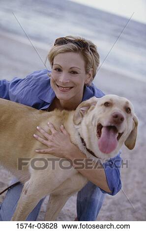 Portrait of a young woman holding her dog on the beach View Large Photo Image Stock Photo - Portrait of a young woman holding her dog on the beach. Fotosearch