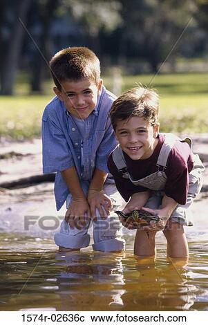 Portrait of two boys standing in water holding a turtle View Large Photo Image Stock Image - Portrait of two boys standing in water holding a turtle. Fotosearch