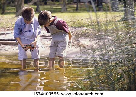 Portrait of two boys standing in water holding a turtle View Large Photo Image Stock Photography - Portrait of two boys standing in water holding a turtle. Fotosearch