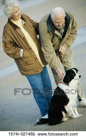 Stock Image - Senior couple standing with their dog on the beach. Fotosearch