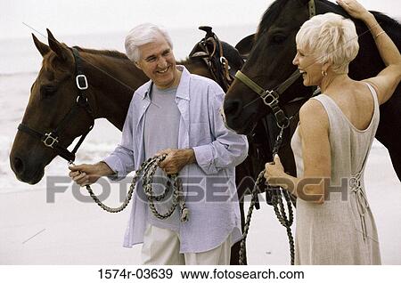 Stock Photo - Senior couple with horses on the beach. Fotosearch