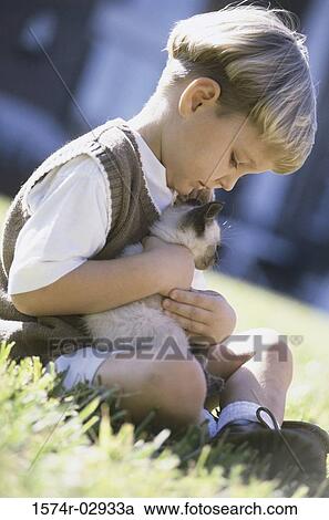 Stock Image - Side profile of a boy holding a Siamese kitten. Fotosearch
