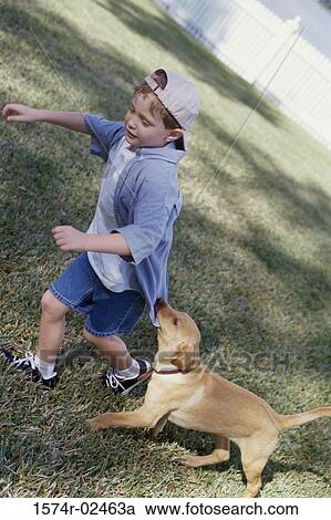 Stock Image - Side profile of a boy playing with his dog. Fotosearch