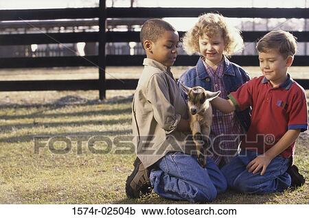 Stock Image - Three children holding a goat. Fotosearch