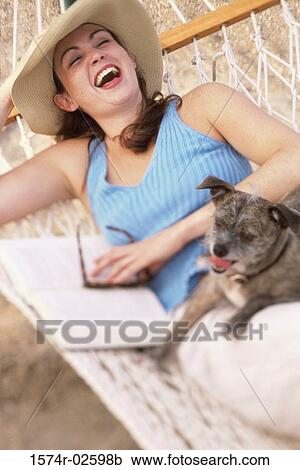 Stock Image - Young woman lying in a hammock with her dog. Fotosearch