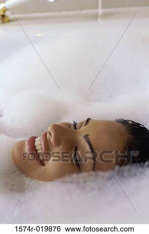 Stock Photograph - Close-up of a young woman taking a bubble bath. Fotosearch