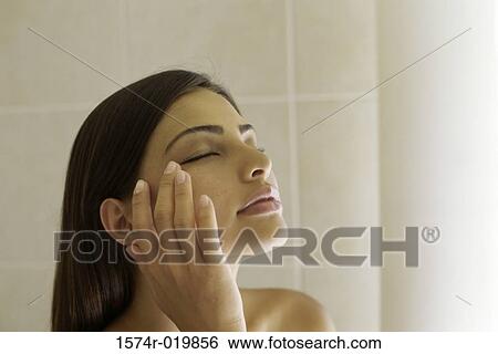 Close-up of a young woman touching her face View Large Photo Image Stock Photograph - Close-up of a young woman touching her face. Fotosearch