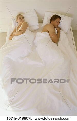 Stock Image - High angle view of a young couple lying on the bed. Fotosearch