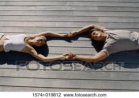 High angle view of a young couple lying on wooden planks holding hands View Large Photo Image Stock Image - High angle view of a young couple lying on wooden planks holding hands. Fotosearch