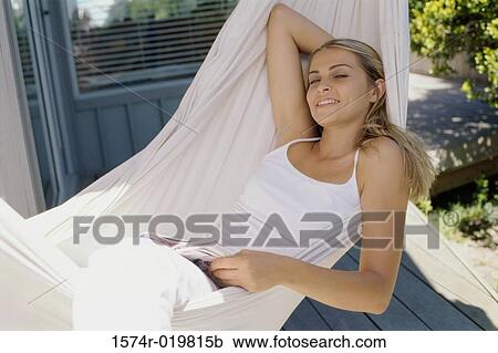 Stock Image - High angle view of a young woman lying in a hammock. Fotosearch