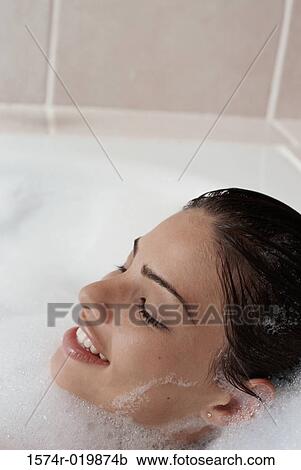 Stock Image - High angle view of a young woman taking a bubble bath. Fotosearch