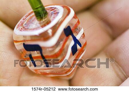 Stock Image - Close-up of a person holding a Jewish dreidel. Fotosearch