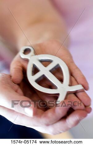 Close-up of a person holding an ichthus fish symbol View Large Photo Image Picture - Close-up of a person holding an ichthus fish symbol. Fotosearch