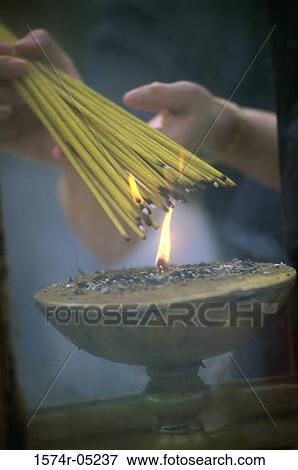 Stock Photo - Close-up of a person's hand lighting incense sticks, Man Mo Temple, Hong Kong, China. Fotosearch
