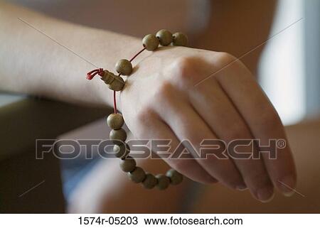 Stock Image - Close-up of a person's hand wearing a Buddhist bracelet. Fotosearch