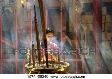 Stock Image - Young woman praying in a temple, Man Mo Temple, Hong Kong, China. Fotosearch