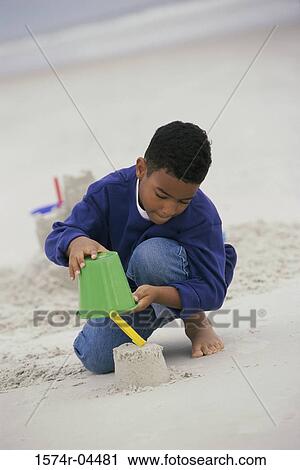 Boy building a sand castle on the beach View Large Photo Image Stock Image - Boy building a sand castle on the beach. Fotosearch