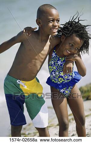Stock Image - Close-up of a girl and a boy holding each other on the beach. Fotosearch
