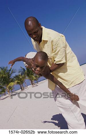 Father carrying his son on the beach View Large Photo Image Stock Image - Father carrying his son on the beach. Fotosearch