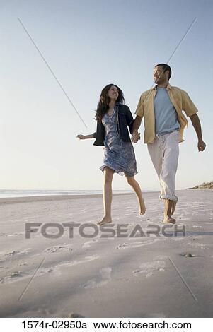 Low angle view of a young couple running together on the beach View Large Photo Image Stock Image - Low angle view of a young couple running together on the beach. Fotosearch