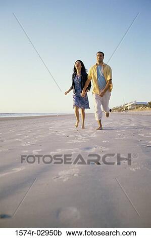 Low angle view of a young couple running together on the beach View Large Photo Image Stock Image - Low angle view of a young couple running together on the beach. Fotosearch