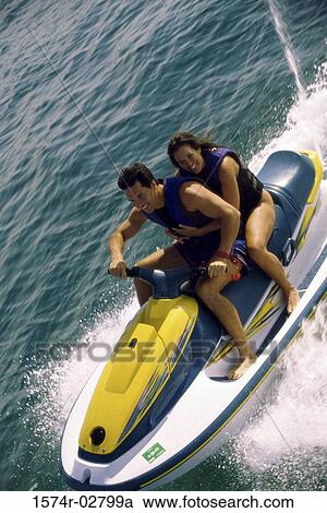 Mid adult couple riding a jet ski in the sea View Large Photo Image Stock Image - Mid adult couple riding a jet ski in the sea. Fotosearch